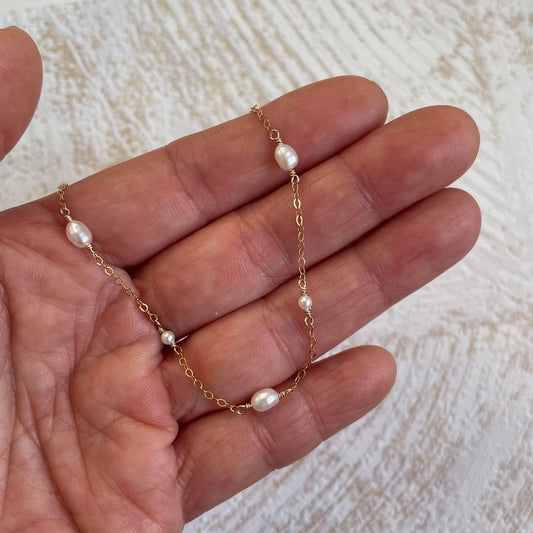 Collier fin en perles blanches dans main